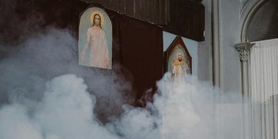 An atmospheric church interior featuring holy paintings shrouded in mist.